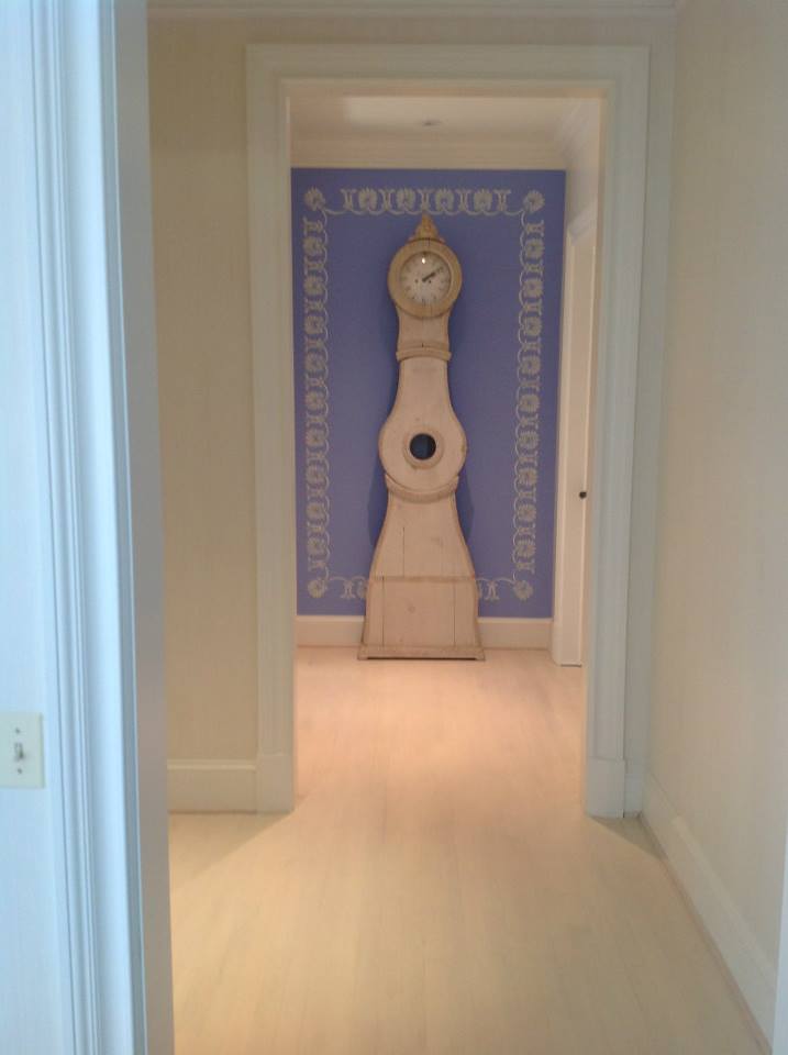 Blue accent wall showcases Gustavian style Swedish grandfather clock. Blue and white pattern hand painted border.
